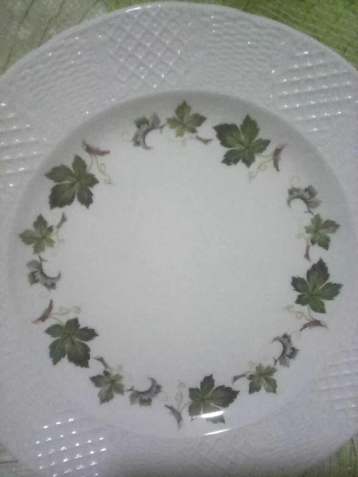 White plate with green leaf pattern on a textured surface
