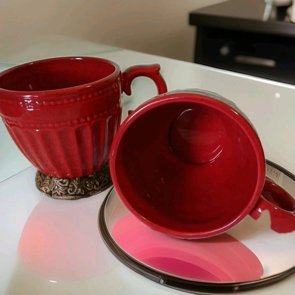Two red ceramic mugs on a white surface