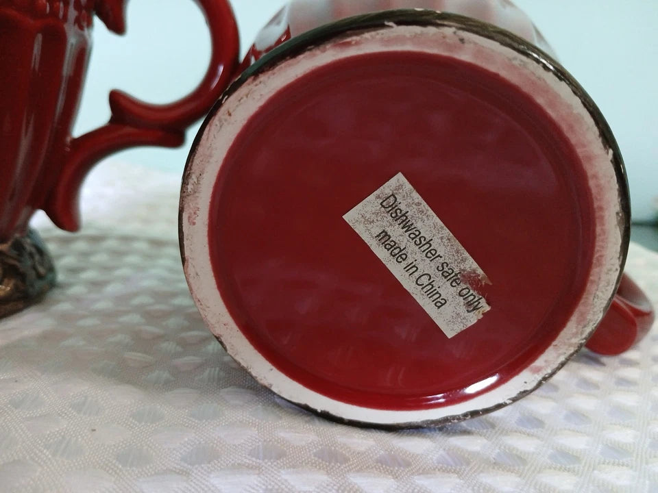 Red mug with a label on the bottom indicating 'Dishwasher safe only made in China' on a textured surface.