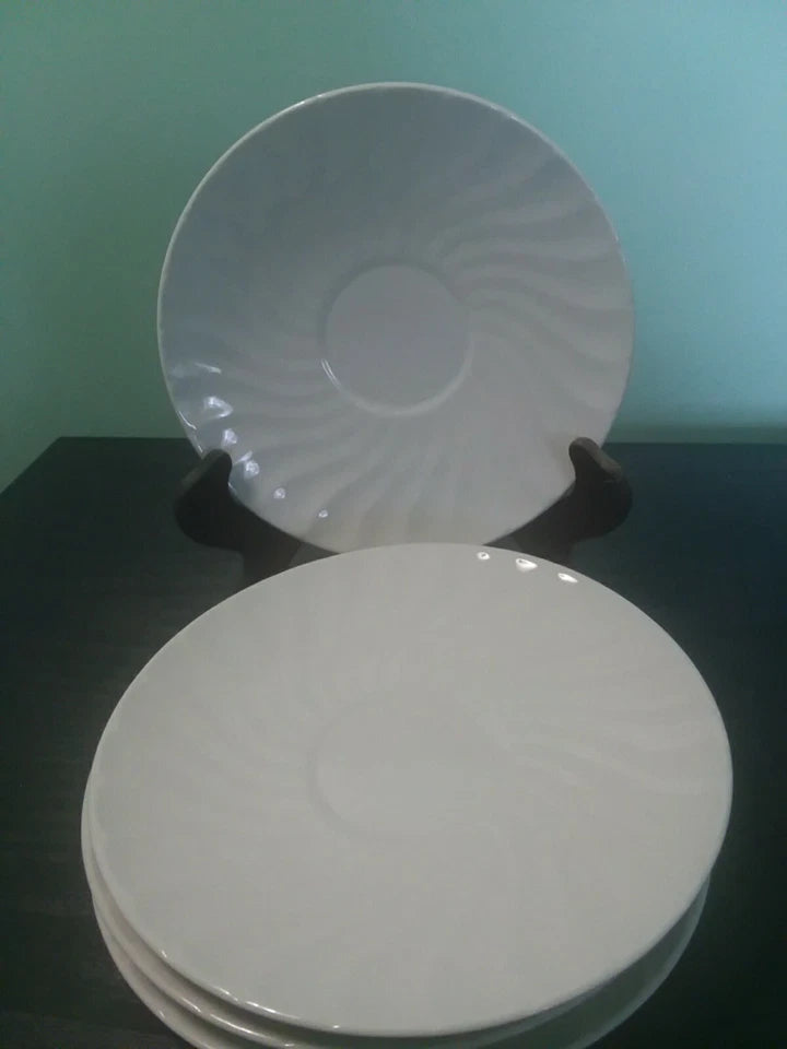 Stack of white ceramic plates on a dark surface with a green wall background