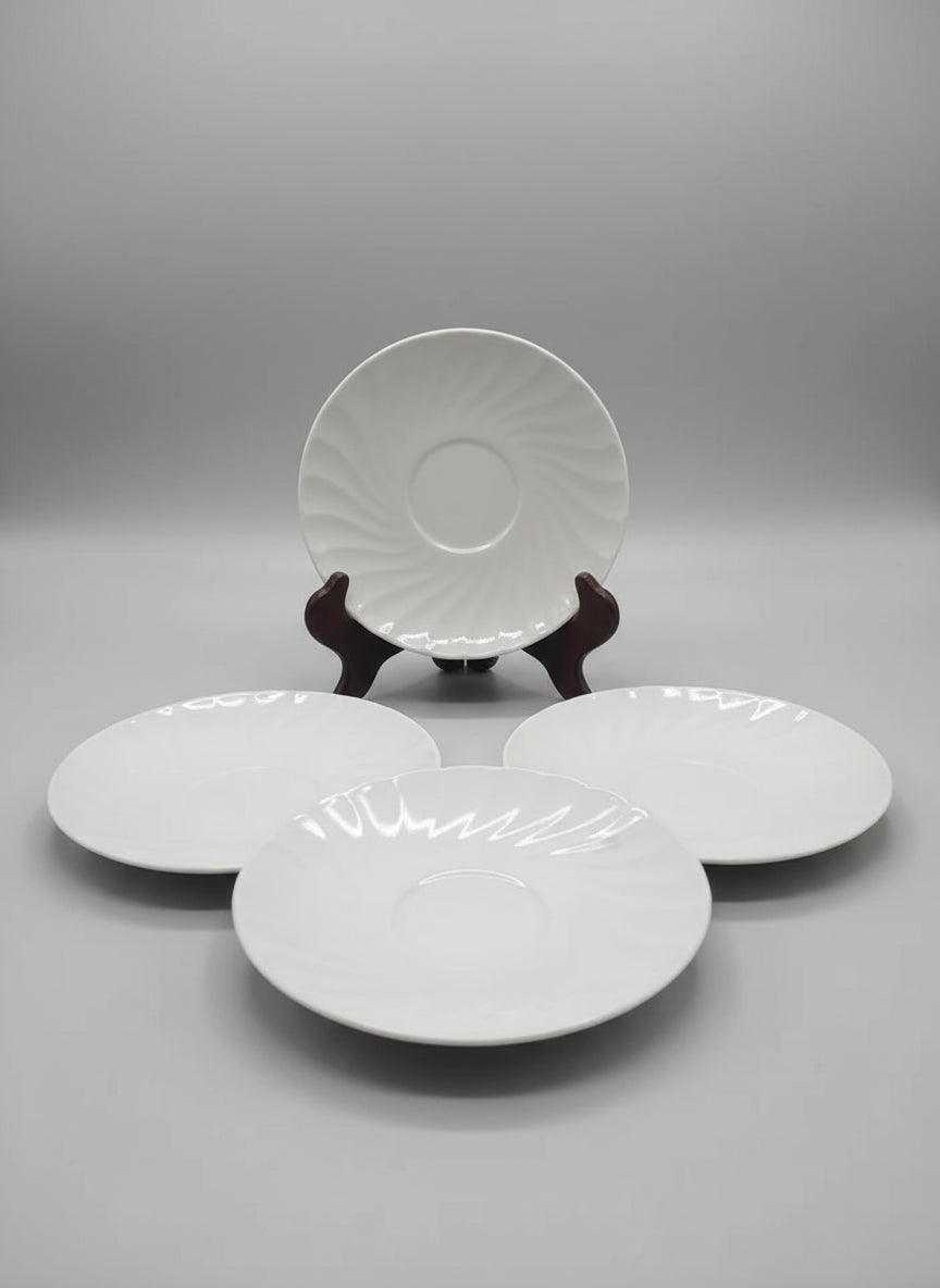 Four white ceramic plates on a dark surface with a light blue wall background