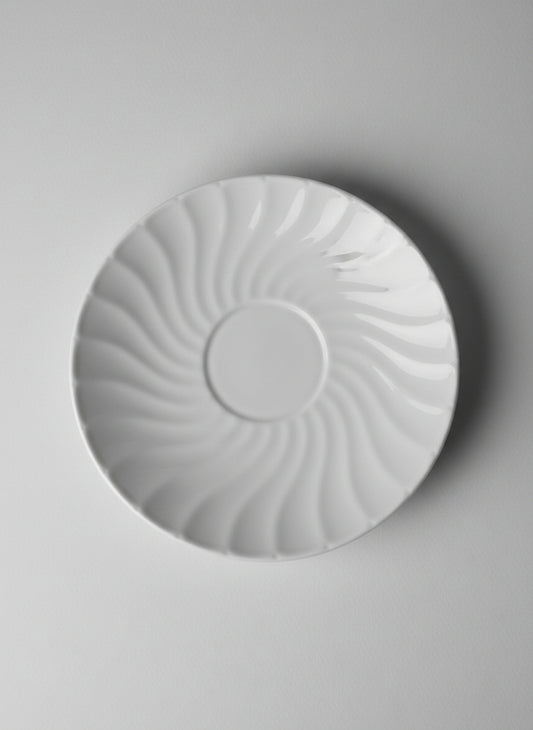 Round white porcline plate on a textured surface green bacground