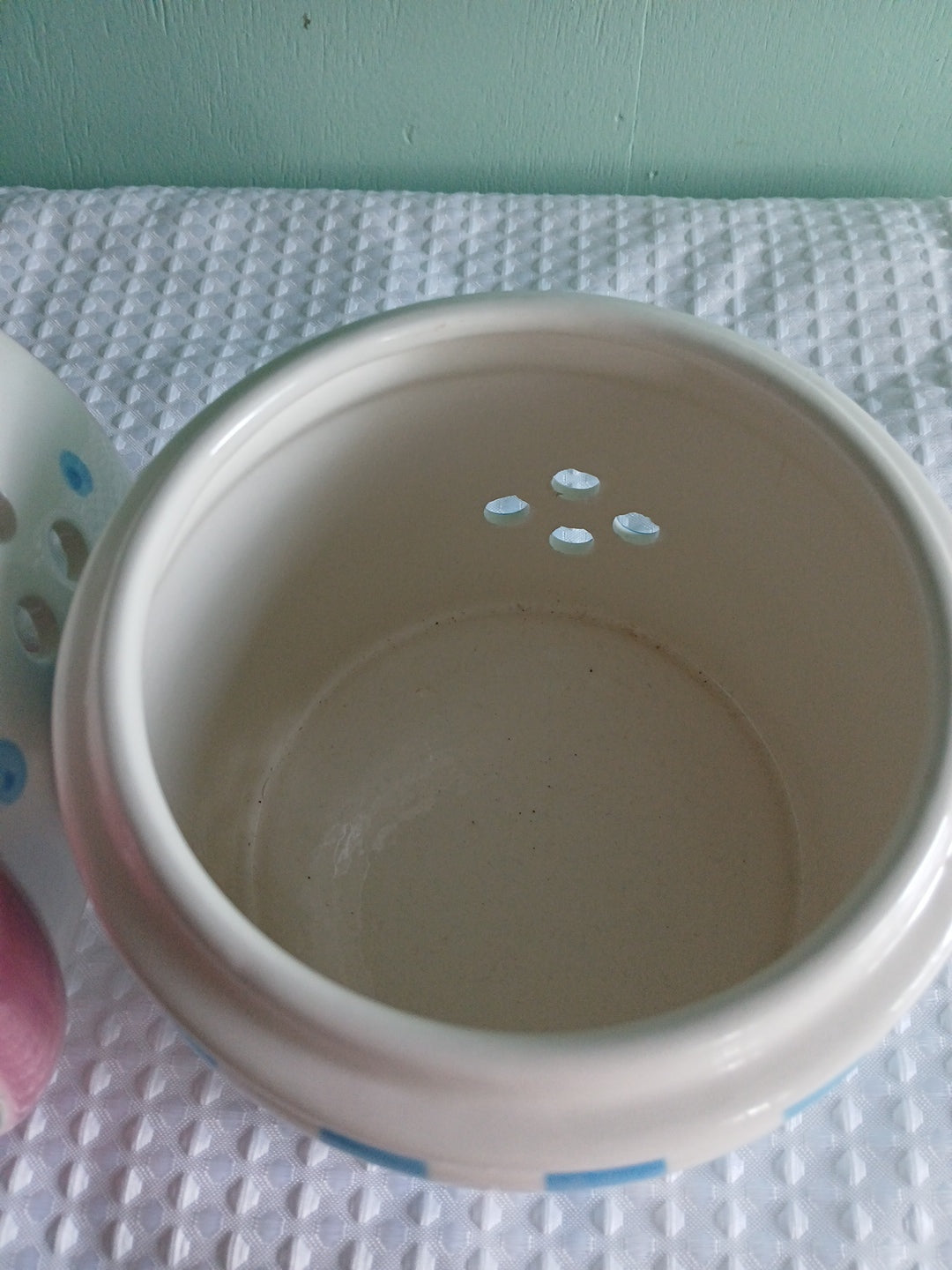 Close-up of a white ceramic candle holder with a textured surface on a textured white background.