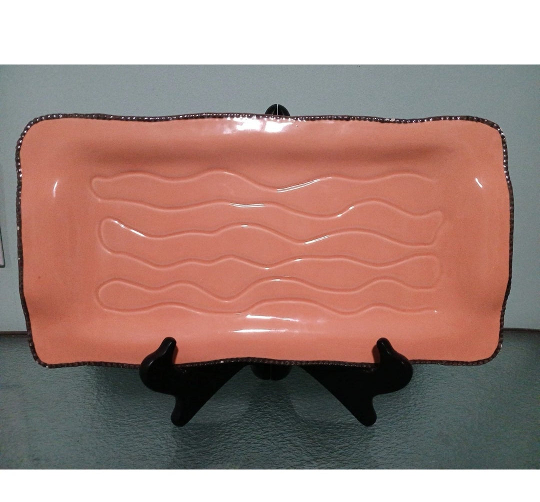 Pink textured rectangular plate on a stand against a gray background