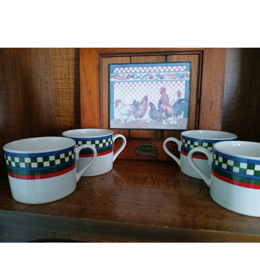 Four ceramic mugs with decorative handles on a wooden surface.