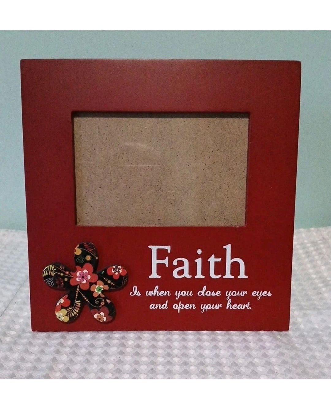 Red picture frame with floral  design and 'Faith' quote on a light blue background
