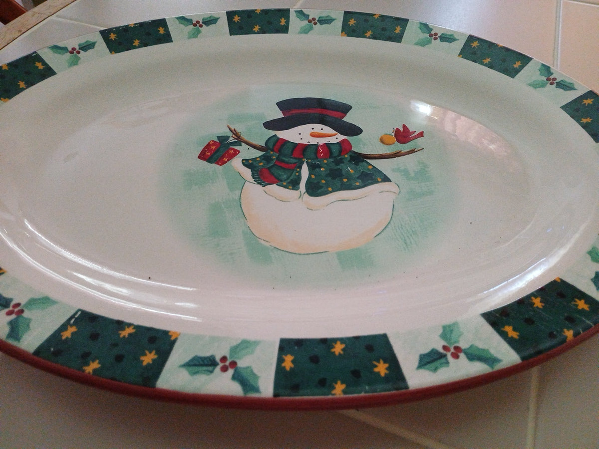 Decorative plate with a snowman design and festive border on a white surface.