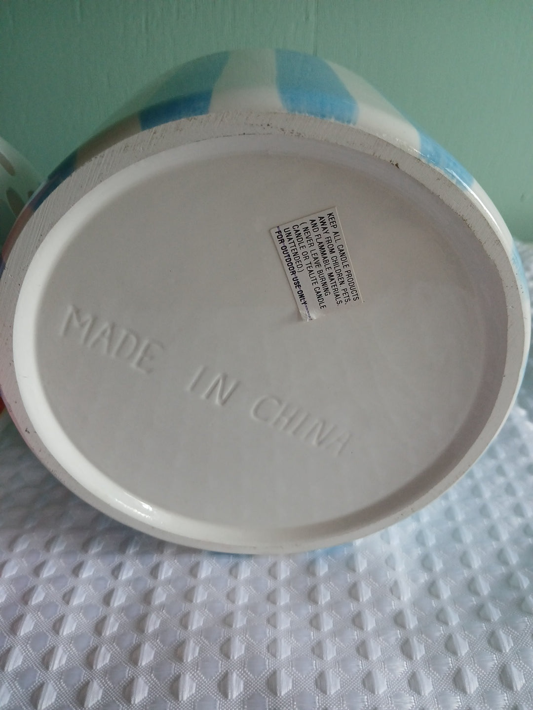 Close-up of a container  candle holder lid with 'Made in China' text on a textured surface.