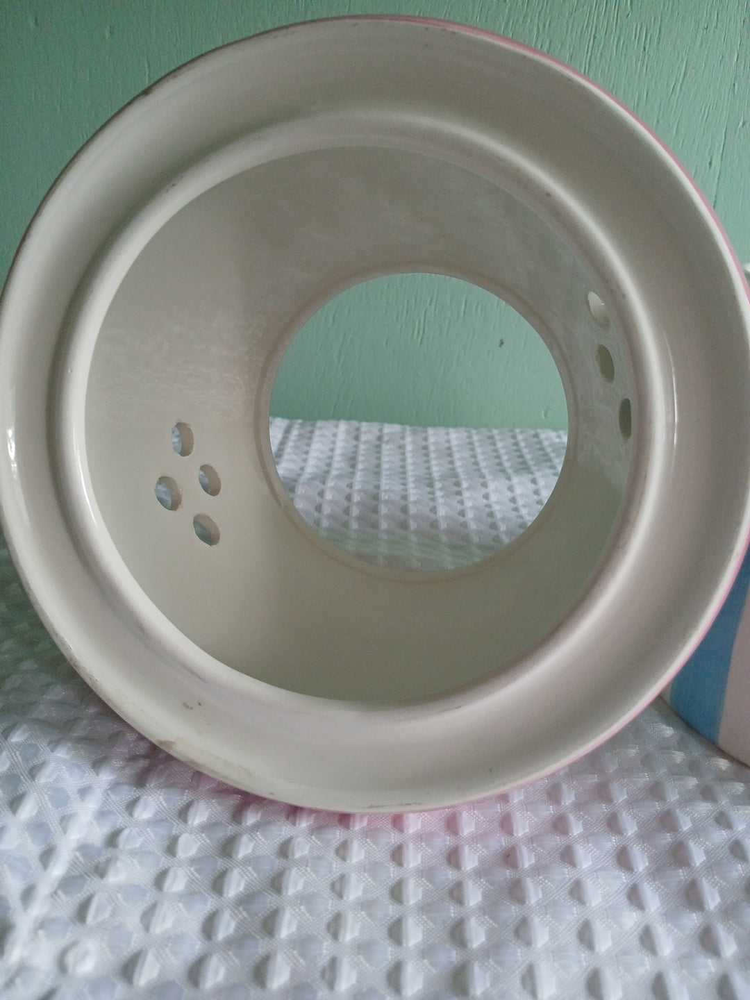 Beige ceramic dish candle holder with holes on a textured surface