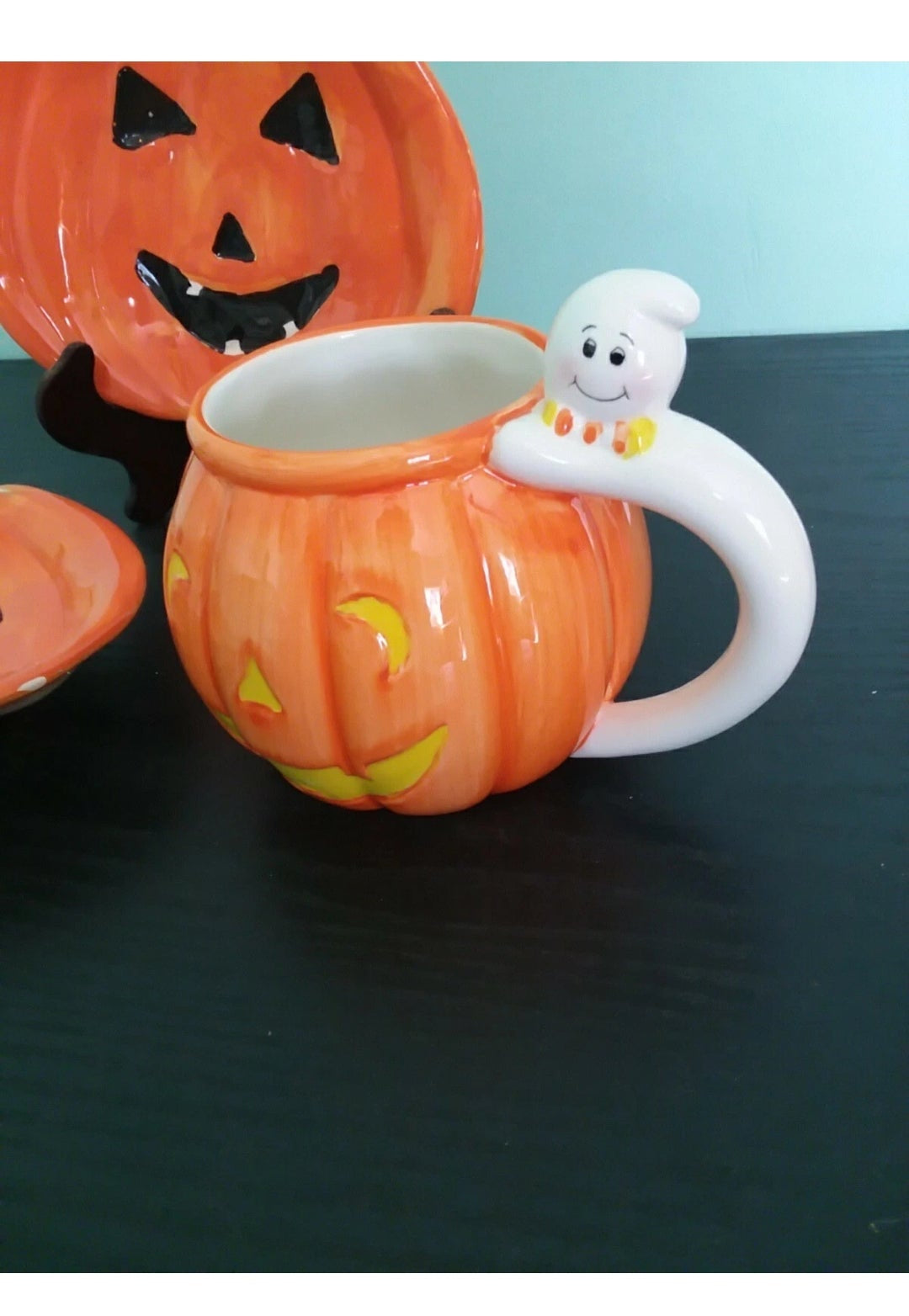Pumpkin-shaped mug with ghost handle on a dark surface
