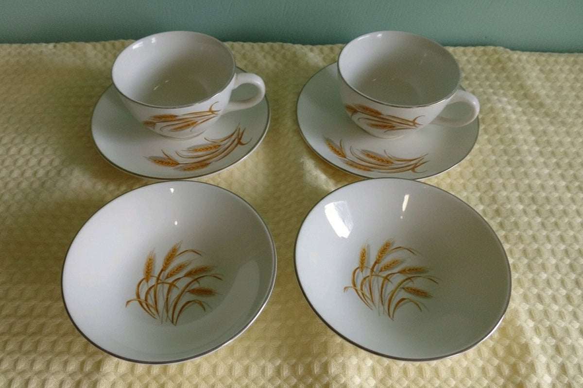 Set of four ceramic dishes with orange floral patterns on a textured surface.
