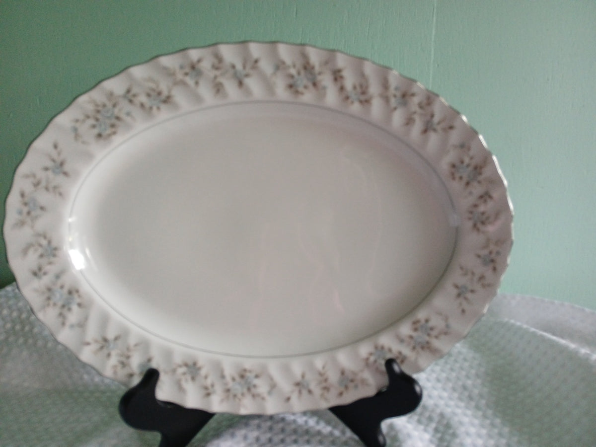Decorative ceramic platter with floral patterns on a stand against a light green background