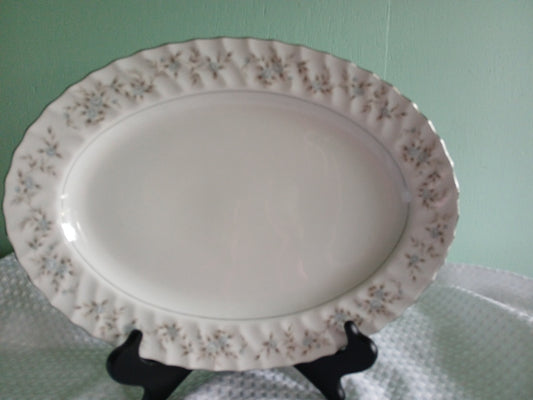Decorative ceramic platter with floral patterns on a stand against a light green background
