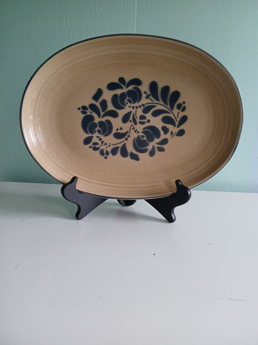 Beige ceramic dish with blue floral pattern on a green wall