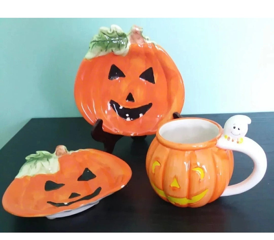 Ceramic pumpkin-themed teapot and cups on a black surface with a light blue background