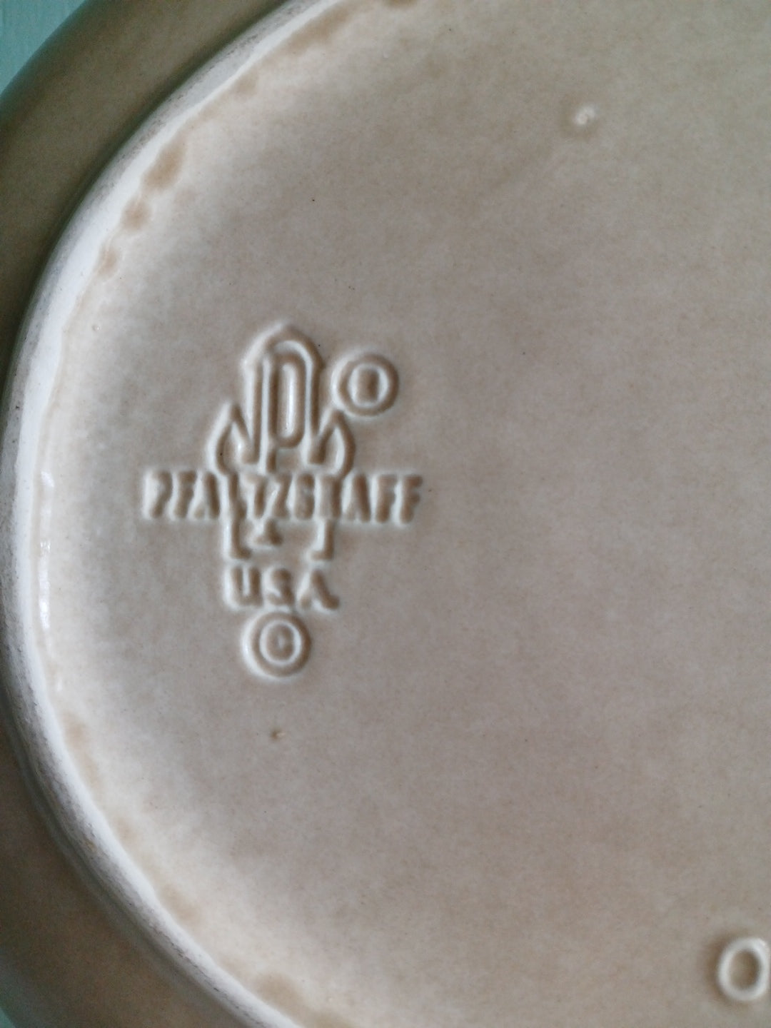 Close-up of a ceramic plate with an embossed logo on a light background