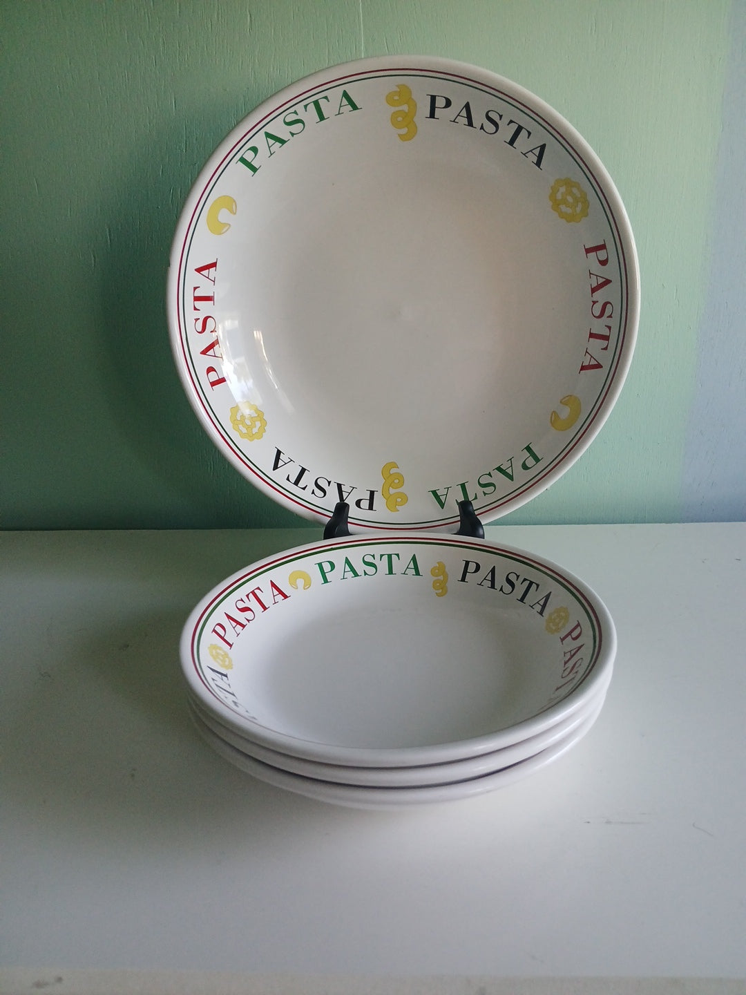 four white ceramic pasta bowls with 'Pasta' text on a green and white background