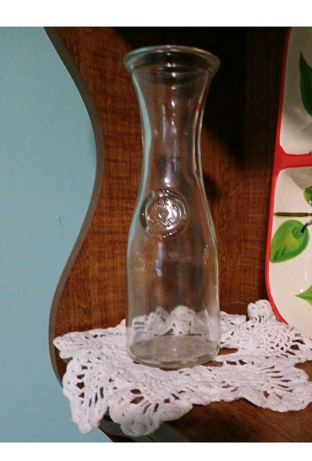 Clear glass vase on a wooden surface with a doily underneath