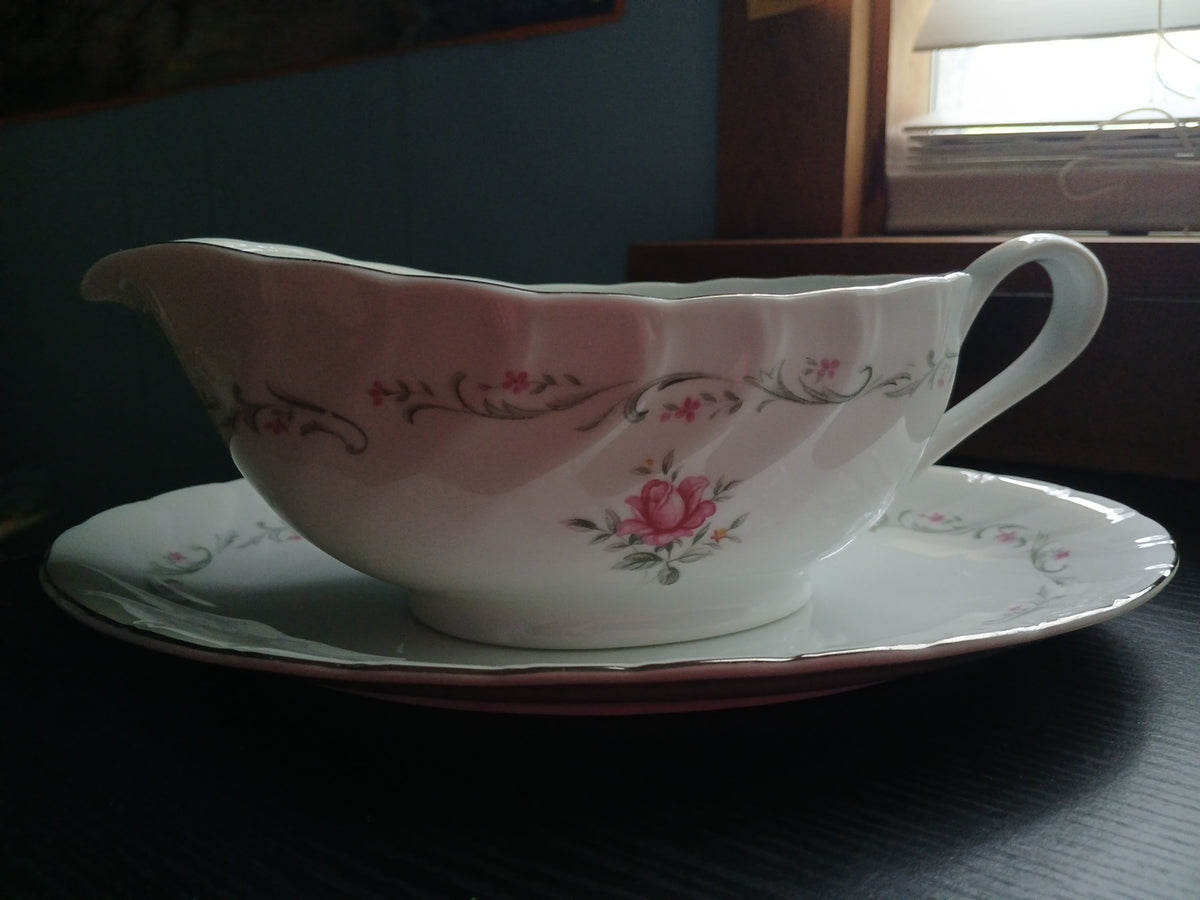 Floral-patterned ceramic gravy boat and saucer on a dark surface