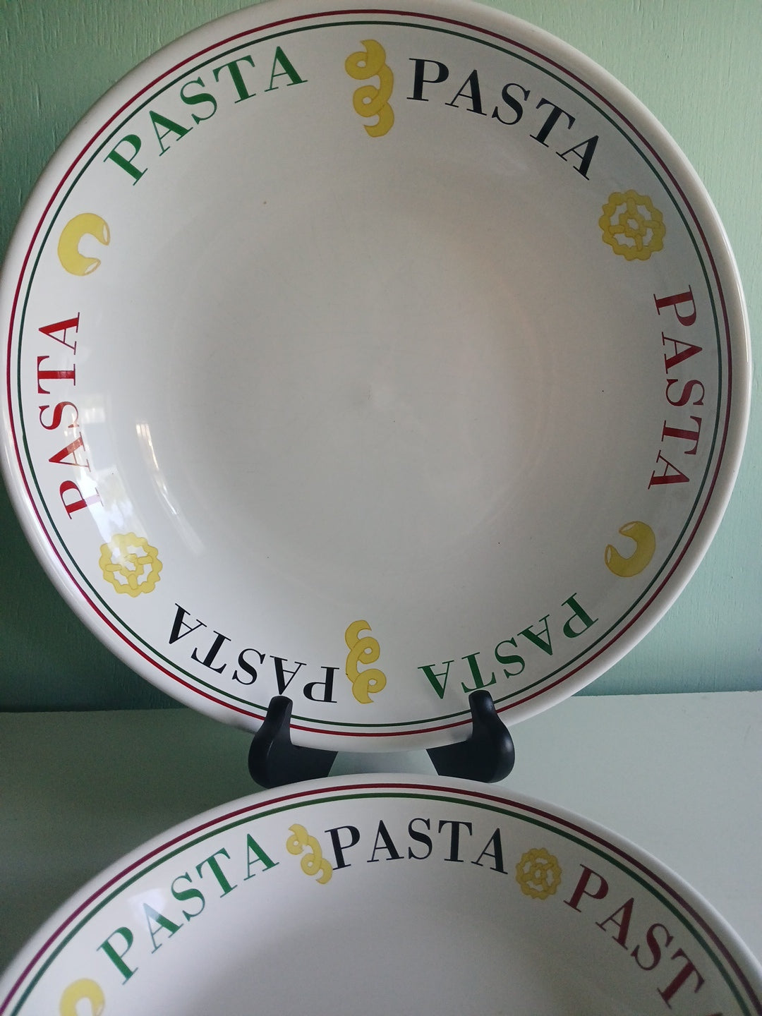 White pasta bowl with 'PASTA' text and yellow symbols on a green background