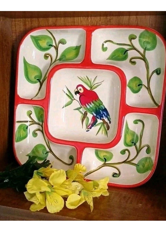 Ceramic plate with a parrot design and green leaves on a wooden surface with yellow flowers.