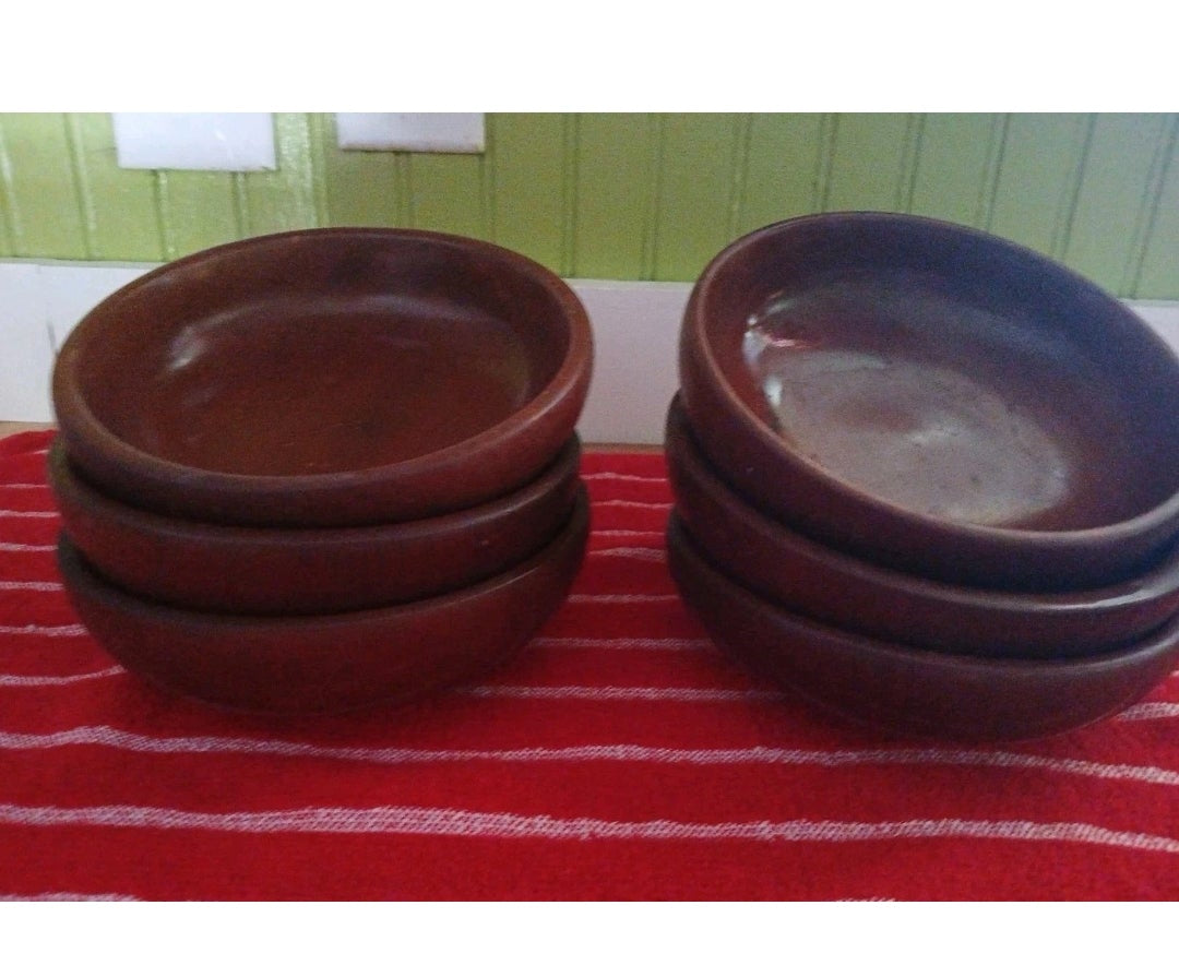 Set of brown  bowls on a red and white striped surface with a green wooden panel background.