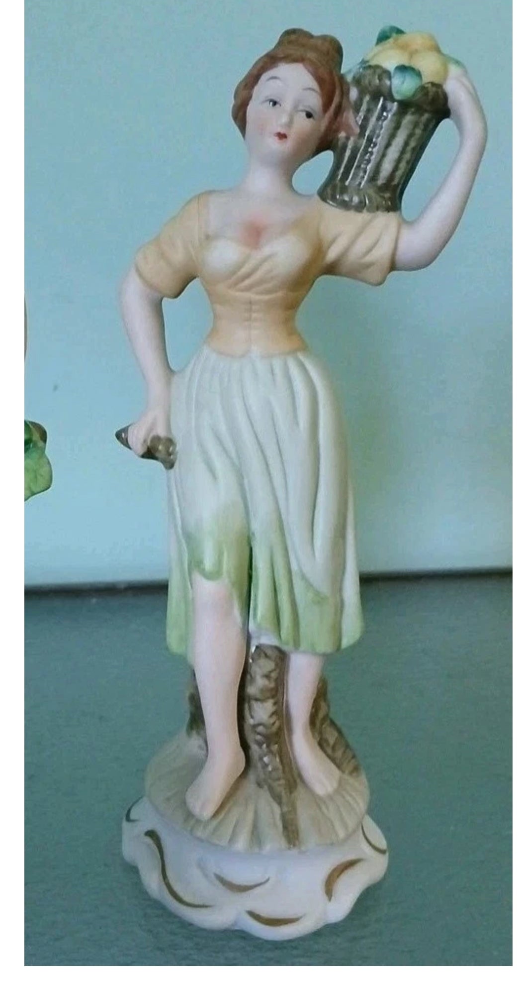 Decorative figurine of a woman holding a basket on a light blue background
