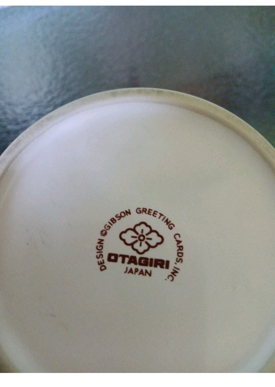 Round beige object with 'Otagiri' branding on a textured surface