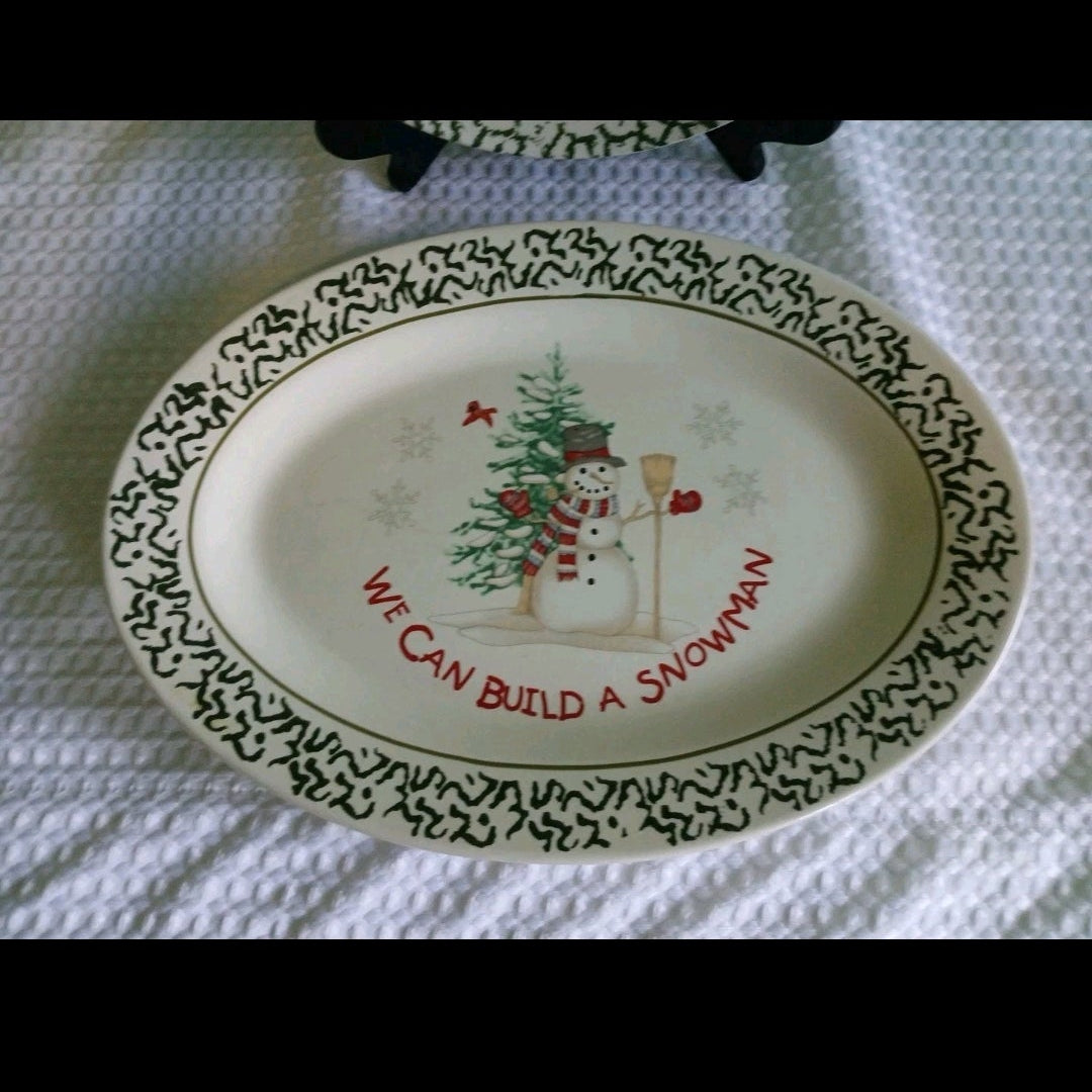 Decorative plate with a snowman and Christmas tree design, text 'We can build a snowman', on a white textured surface.