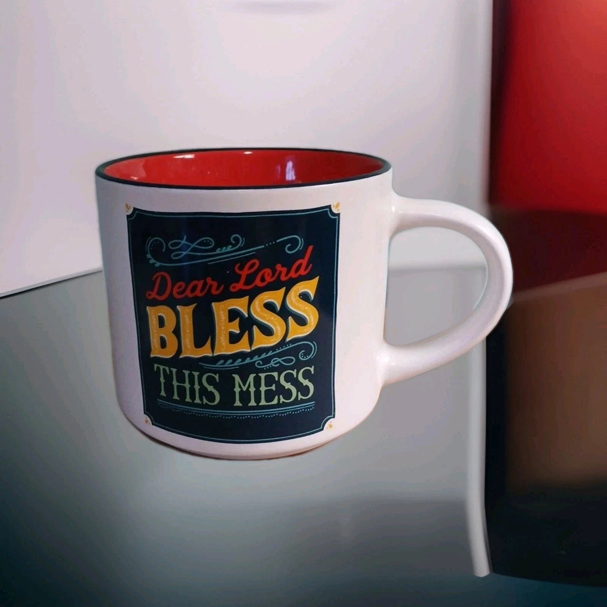 Mug with 'Dear Lord BLESS this mess' text on a reflective surface.