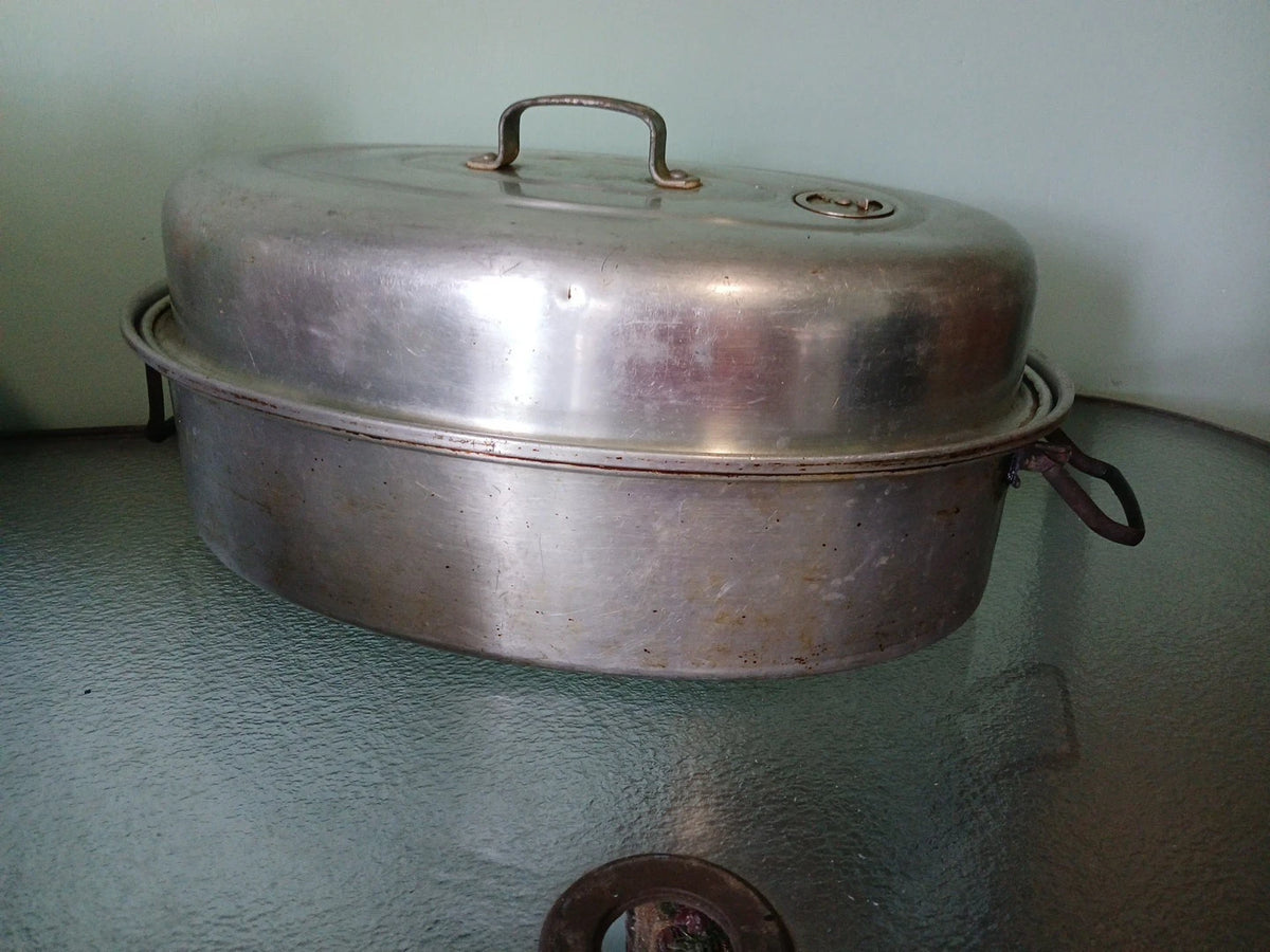 Vintage metal roasting pan with lid on a textured surface