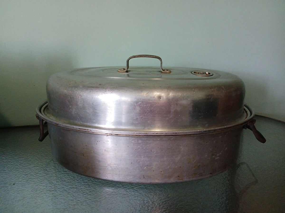 Vintage metal roasting pan with lid on a green surface