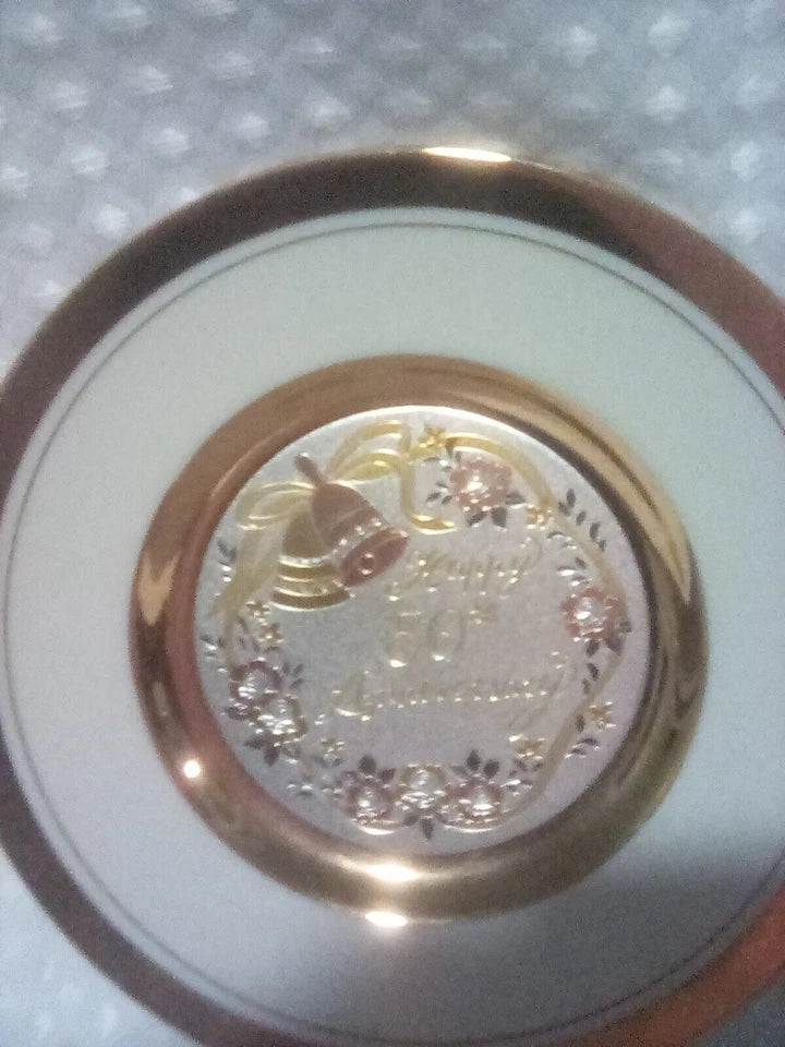 Round decorative item with gold rim and central design on a textured white background