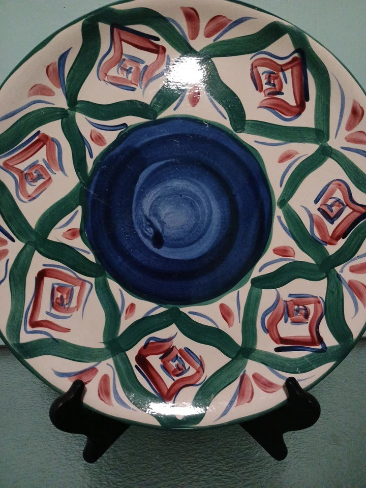 Decorative ceramic plate with geometric pattern on a stand against a light blue background