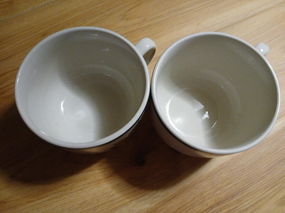 Two white ceramic cups on a wooden surface
