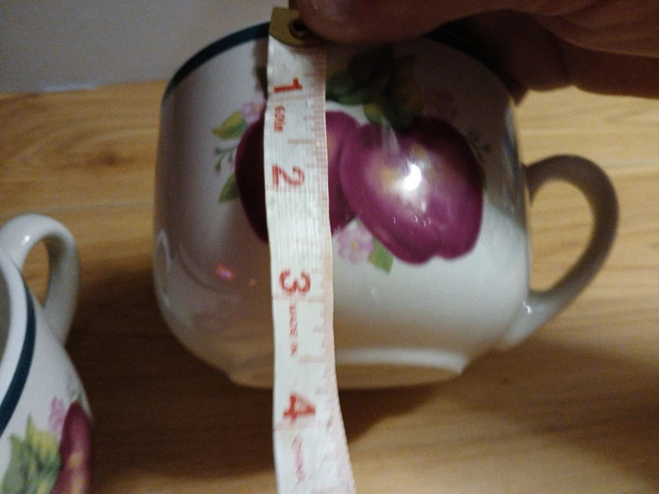 Ceramic mug with floral design on a wooden surface, with a measuring tape indicating its size.
