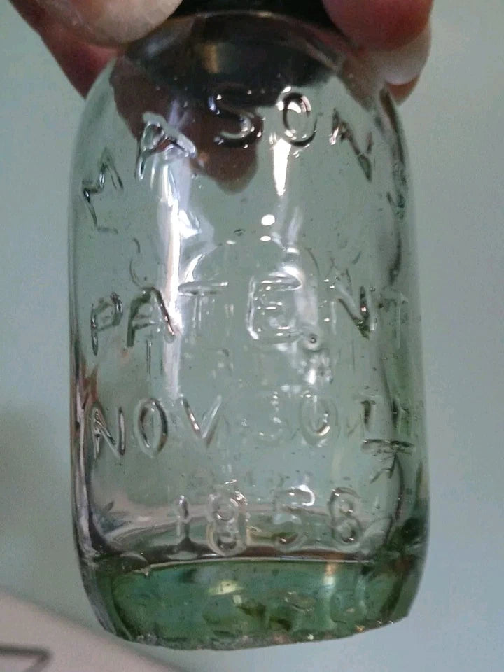 Clear glass Mason jar with embossed text on a white background