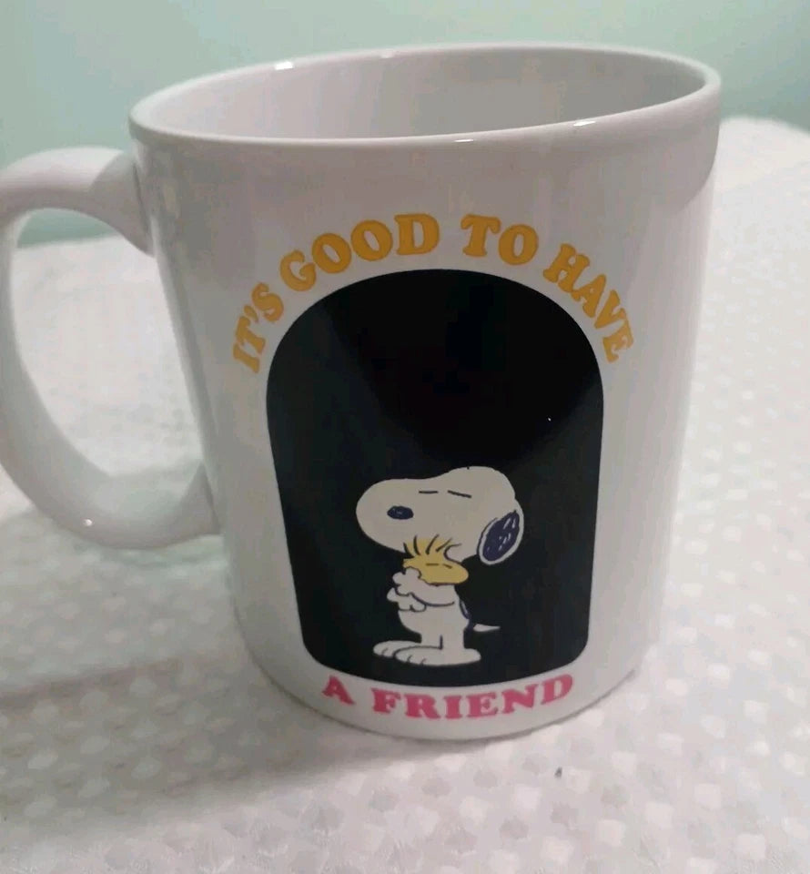 White mug with Snoopy design and text 'It's good to have a friend' on a white background