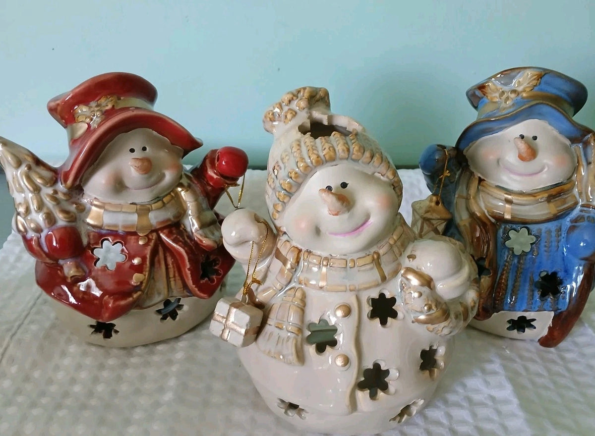Three decorative snowman figurines with different outfits on a light blue background.
