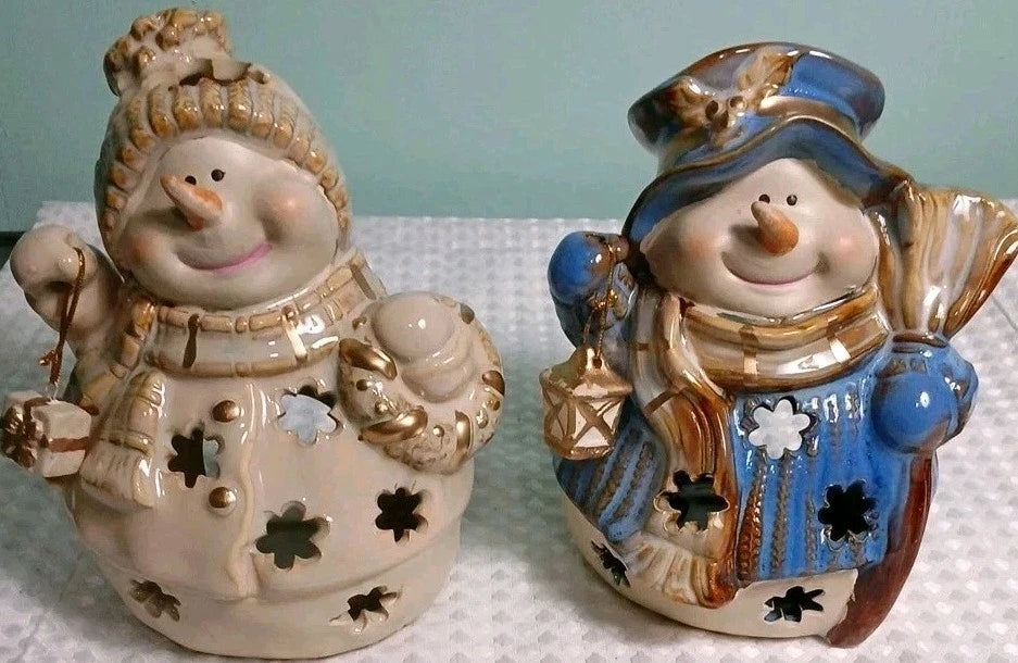 Two ceramic snowman figurines with decorative clothing on a light background