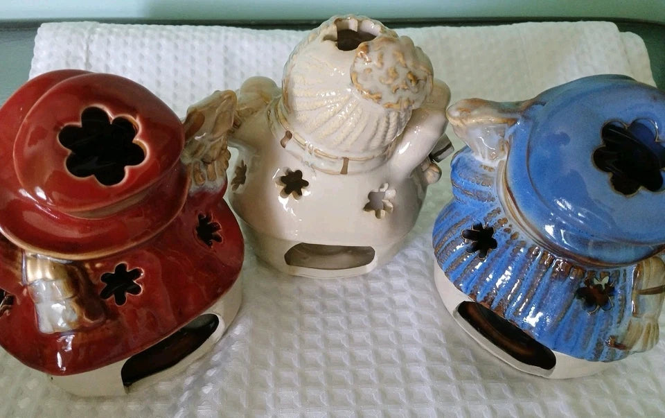 Three ceramic incense burners in red, white, and blue on a textured surface.