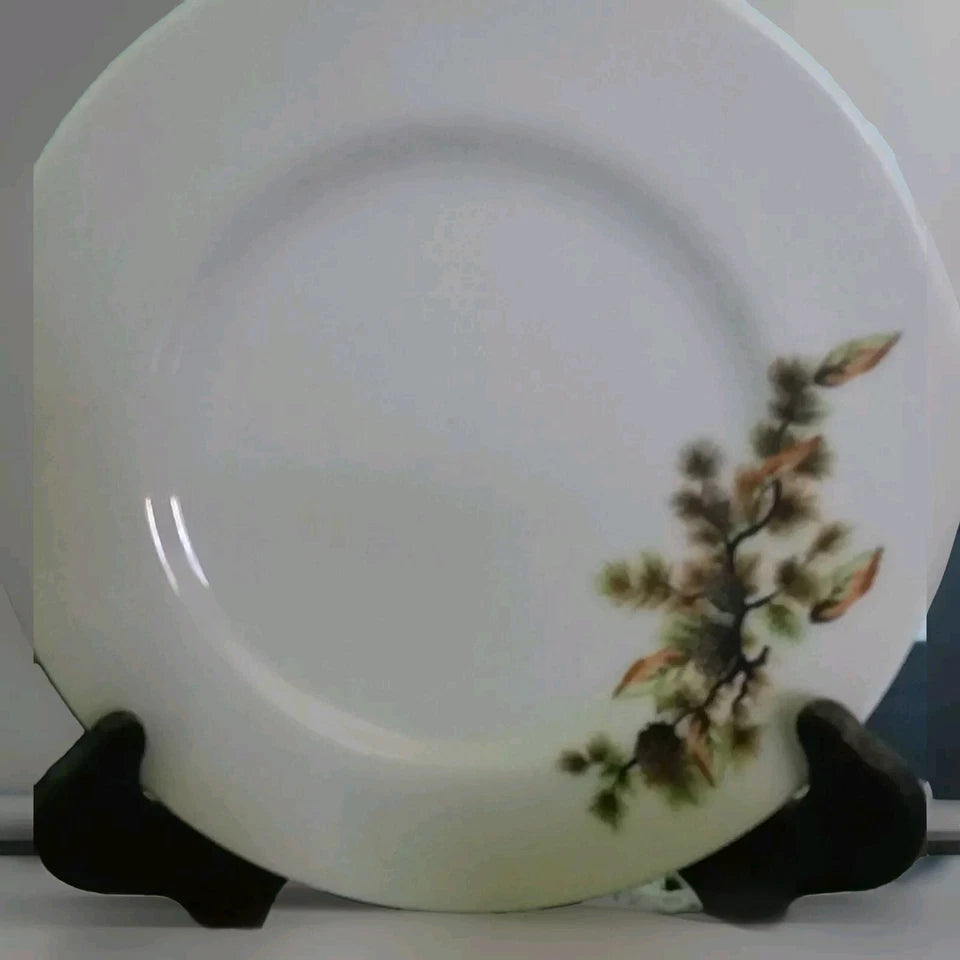 White ceramic plate with floral design on a stand against a neutral background