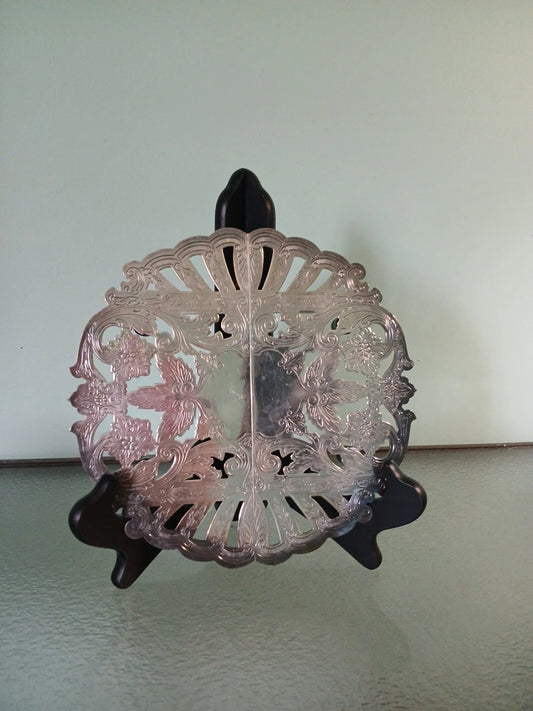 Decorative metal trivet on a stand against a plain background