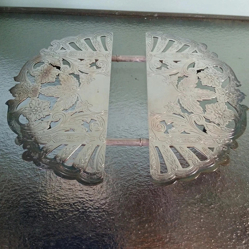 Decorative metal grates with intricate cut-out patterns on a reflective surface.